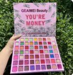 A large makeup kit displaying 63 square pans of highly pigmented eyeshadows, showcasing vibrant shades of blues, teals, greens, and purples in matte, shimmer, and glitter finishes.